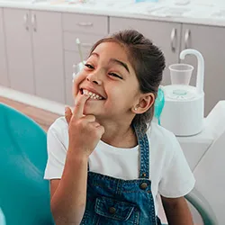 A young child showing off her clean teeth to her dentist during a dental appointment after fluoride was applied.