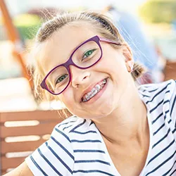 a young girl smiling after starting a braces treatment plan to help bring out her best smile