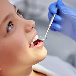 A close up view of a dental professional using a mirror to check the back of a patients teeth